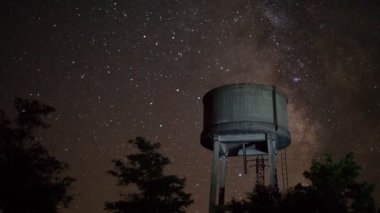 Hareketli yıldızlarla harap olmuş beton su tankı gece vakti doluyor.