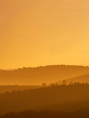 Tepeler gün batımında turuncu renklerle sıkıştırılmış çekim yapar