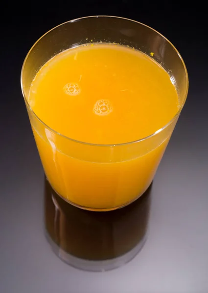 Вид зверху на апельсиновий сік над чорним і скляним відображенням — стокове фото