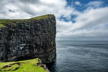 Okyanusun üzerinde turistlerle dolu kocaman dik kayalıklar.