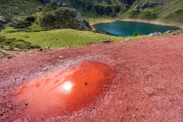 Червона калюжа з відбиттям сонця і озером — стокове фото