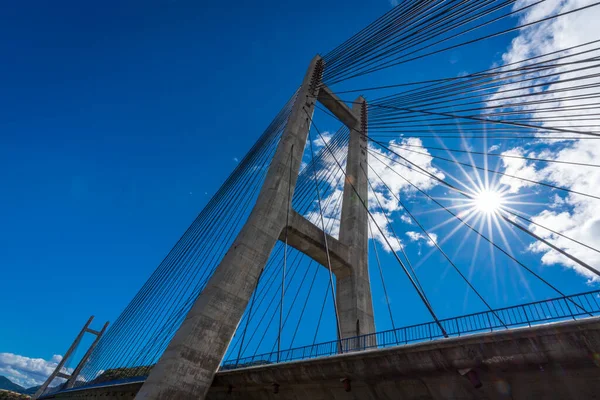 Cable suspension bridge over reservoir with sunstar — Stock Photo, Image