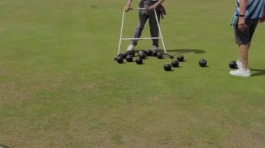 İki kriket oyuncusu, takım çalışmasını gösteren bir turdan sonra topları toplamak için yarı çember kullanıyor..