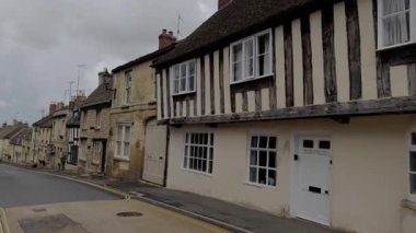 Büyüleyici bir caddede klasik taş kulübelerle yürüyorum Cotswold İngiliz köyünde.