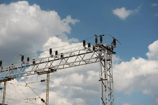 Train or railway power line support. Railway power lines with high voltage electricity on metal poles against blue sky.