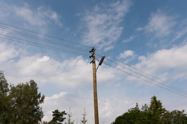 Tahta sokak lamba sonrası beyaz bulutlar ile mavi gökyüzü karşı elektrik telleri ile