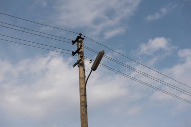 Tahta sokak lamba sonrası beyaz bulutlar ile mavi gökyüzü karşı elektrik telleri ile