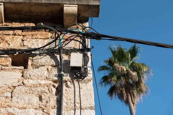 Elektrik telleri üzerinde eski bir taş ev bağlı. Eski mimari. Elektrik iletim. Binanın üzerinde ampul. Sokak ışık.