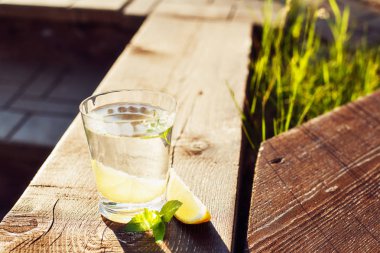 Limon ve nane, güneşli bir günde bir ahşap tahta üzerinde temiz su