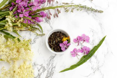 Porcelain Cup with dry herbal Ivan-tea with Fireweed and Meadowsweet on the marble table. Harvesting. clipart