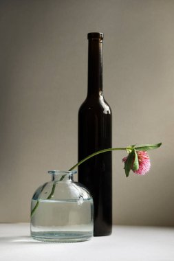Siyah şişe ve solmuş kırmızı yonca çiçeğiyle dolu bir hayat. Seçici ve yumuşak odak.