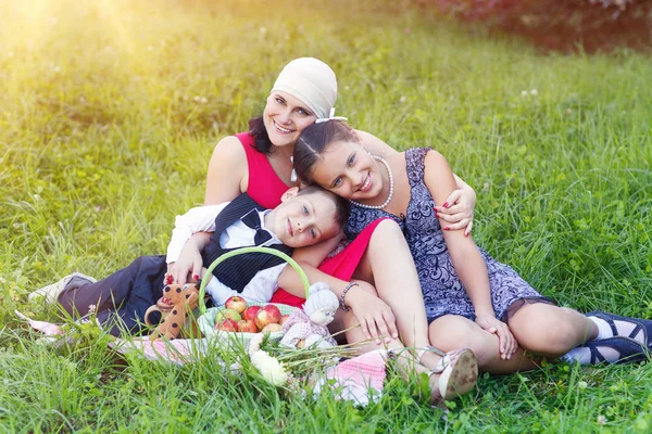 Мать с двумя детьми устраивает пикник на открытом воздухе — стоковое фото