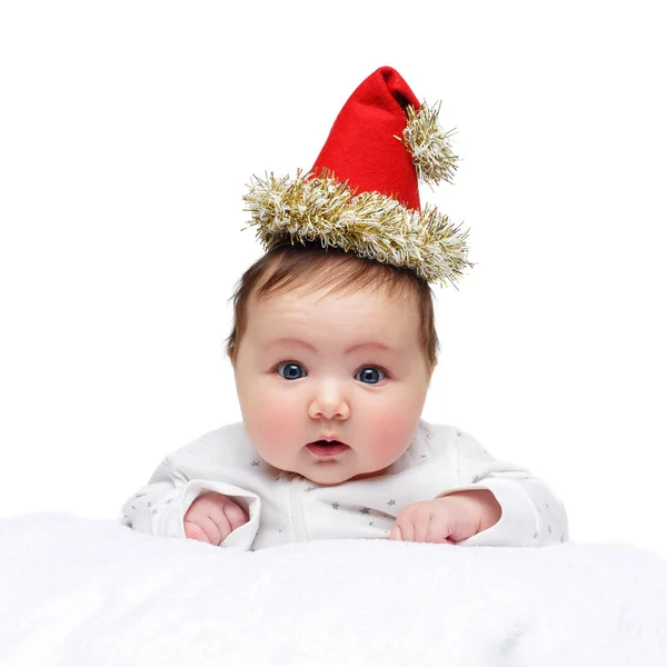 Schönes kleines Mädchen mit Weihnachtsmütze auf weißer Decke — Stockfoto