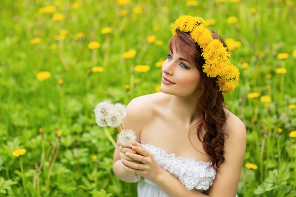 Vacker flicka med maskros blommor i grönt fält — Stockfoto