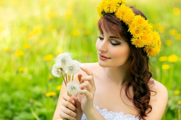 Vacker flicka med maskros blommor i grönt fält — Stockfoto