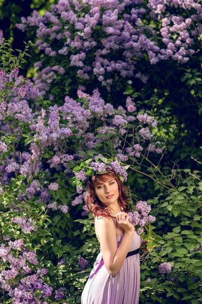 Schönes Mädchen in lila Kleid mit lila Blüten — Stockfoto