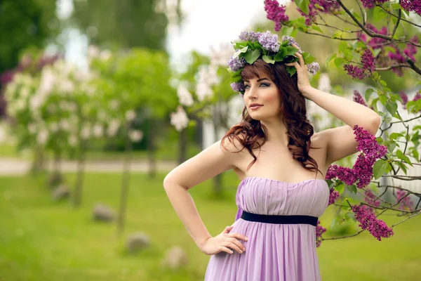 Красивая девушка в фиолетовом платье с цветами сирени — стоковое фото