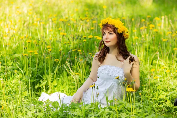 Mooi meisje met paardebloem bloemen in groene veld Stockfoto