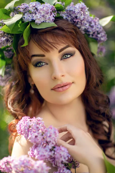 Mooi meisje in een paarse jurk met lila bloemen Stockfoto