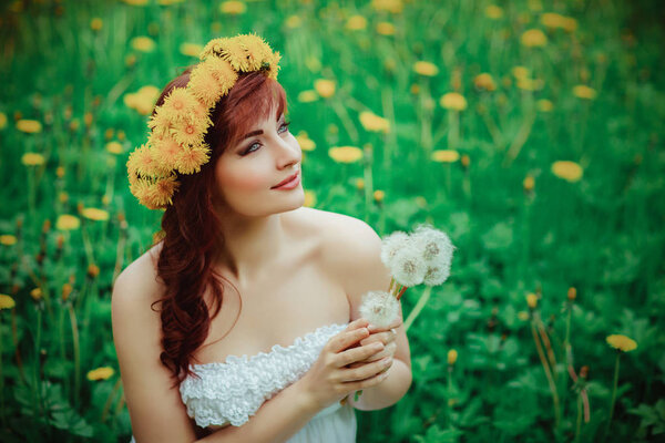 Beautiful young woman with dandelion flowers in green field. outdoor summer shot. copy space.