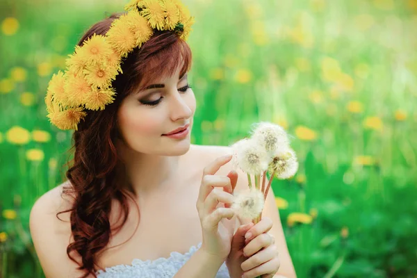 Vacker flicka med maskros blommor i grönt fält — Stockfoto