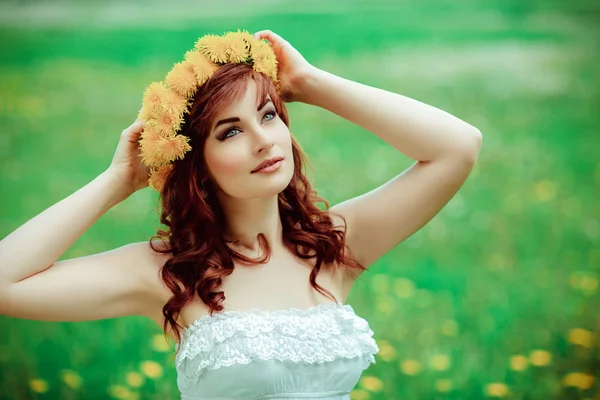 Bella ragazza con fiori di tarassaco in campo verde — Foto Stock