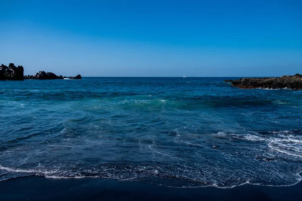 Belle vue sur l'eau de l'océan et le sable de lave noir — Photo