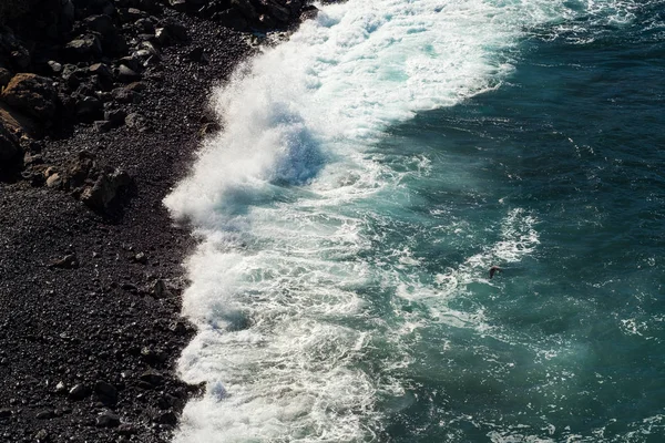 Belle vue sur l'eau de l'océan et le sable de lave noir — Photo