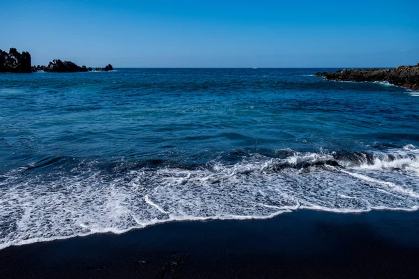 Prachtig uitzicht op de oceaanwater en zwart lava zand — Stockfoto