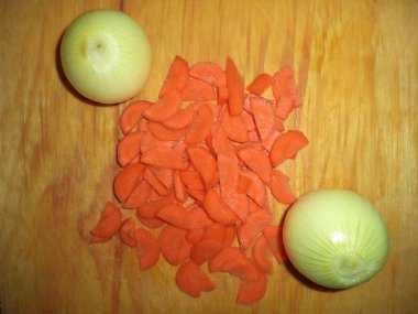 bir kesme tahtası üzerinde iki soğan ve havuç yarım halkalı