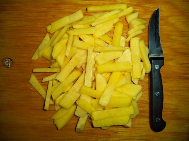 bir kesme tahtasında şeritler halinde kesilmiş çiğ patates