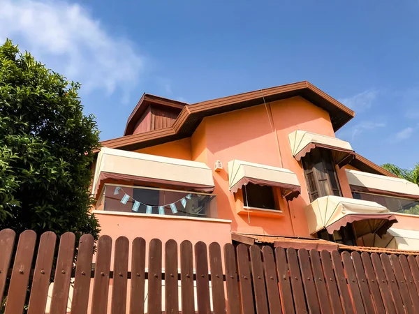 RISHON LE ZION, ISRAEL -30 DE ABRIL DE 2018: Una hermosa casa de color con una gran valla de madera y piedra y grandes árboles de flores cerca de ella . — Foto de Stock