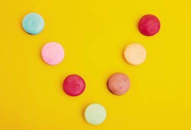 Tasty farklı macarons sarı arka plan üzerinde renkli.   