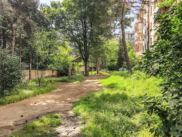 A estrada que entra no pátio do edifício residencial, o quintal com árvores florescentes e alcova — Fotografia de Stock