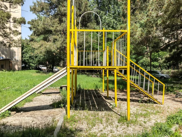 TBILISI, GEORGIA - - 17 DE MAYO DE 2018: Parque infantil para juegos. Construcción de hierro en el patio cerca del edificio residencial. Primavera en la ciudad . — Foto de Stock