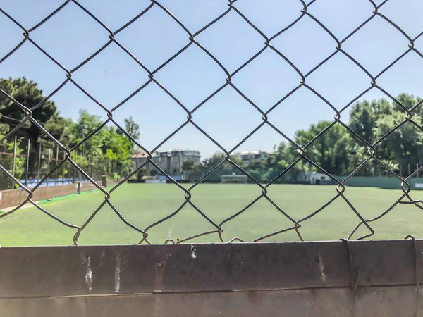 Grade de ferro, esgrima em torno do estádio de futebol entre edifícios residenciais. Primavera na cidade — Fotografia de Stock