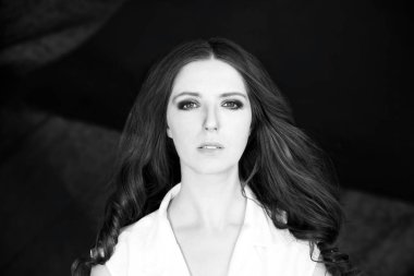 Güzel kadın Beyaz gömlekli stüdyo çekimi koyu arka plan üzerinde durmak.