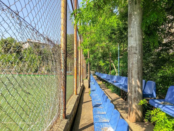 Bancos de plástico e árvores floridas no parque da cidade perto do estádio — Fotografia de Stock