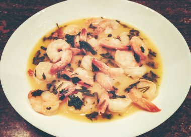 Masanın üzerinde beyaz bir tabak karides çorbası.