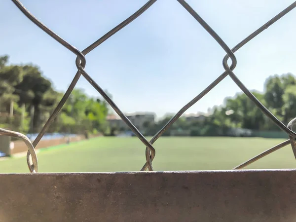 Grade de ferro no fundo de um campo de futebol e céu. Fechar tiro — Fotografia de Stock