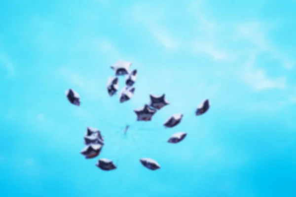 Blur silver balls in the form of a star fly into the blue sky — Stock Photo, Image