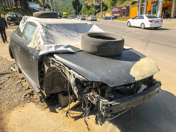 Tiflis, Gürcistan--17 Mayıs 2018: kaput lastiği ile branda ile kaplı araba kırık eski bir yola park