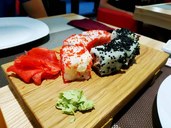 Sushi roll comida japonesa en el restaurante. California Sushi rollo conjunto con salmón, verduras, huevas de pescado volador y caviar primer plano —  Fotos de Stock
