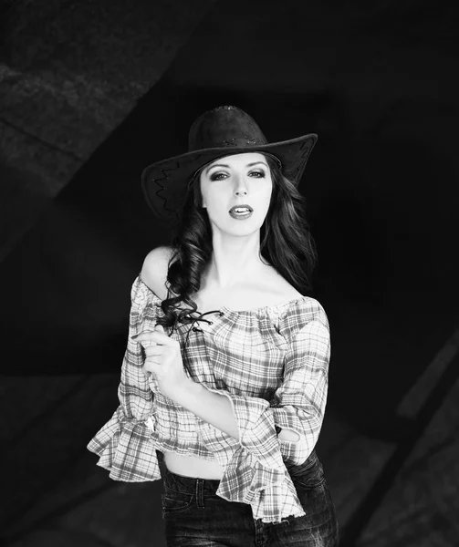 Schöne brünette Cowgirl in Cowboy-Hut auf dunklem Hintergrund. — Stockfoto