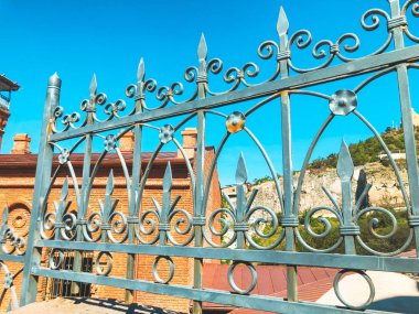 Tbilisi binalar sokakta. Güzel Iron gate karşı tuğla duvar yaz gün
