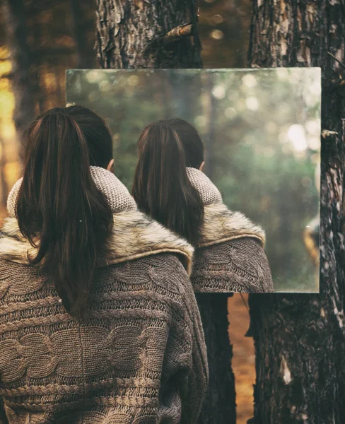 The girl looks in the mirror. Strange display in it. Forest space