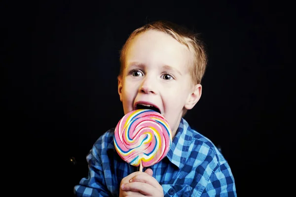 Kleiner Junge mit Lutscher auf schwarzem Hintergrund — Stockfoto