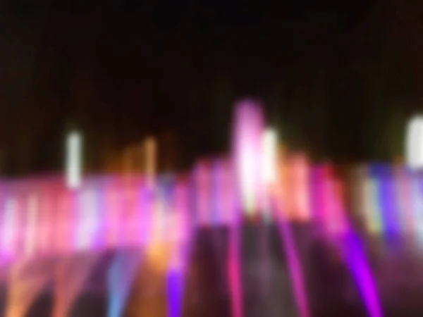 La fuente parpadea, iluminada por luces de colores por la noche. Fondo abstracto en diferentes tonos de colores . — Foto de Stock