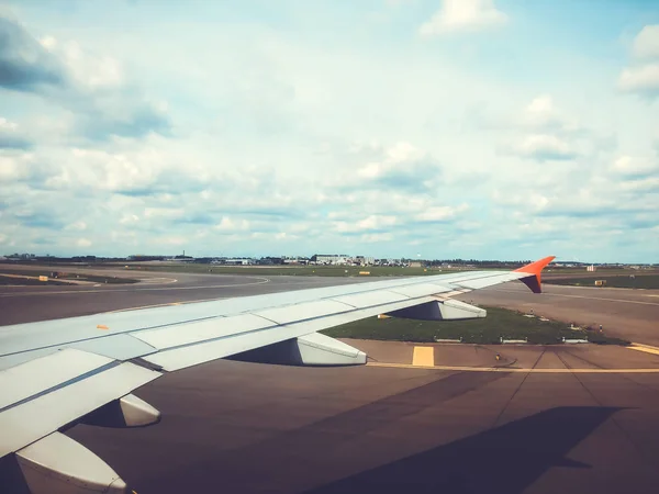 Vleugel van het vliegtuig in Amsterdam airport. Vliegtuig is op de baan. Het vliegtuig neemt af of landing. — Stockfoto