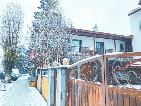 Portão de madeira com guarnição de aço decorativo. Neve cai na rua.Meio-dia — Fotografia de Stock